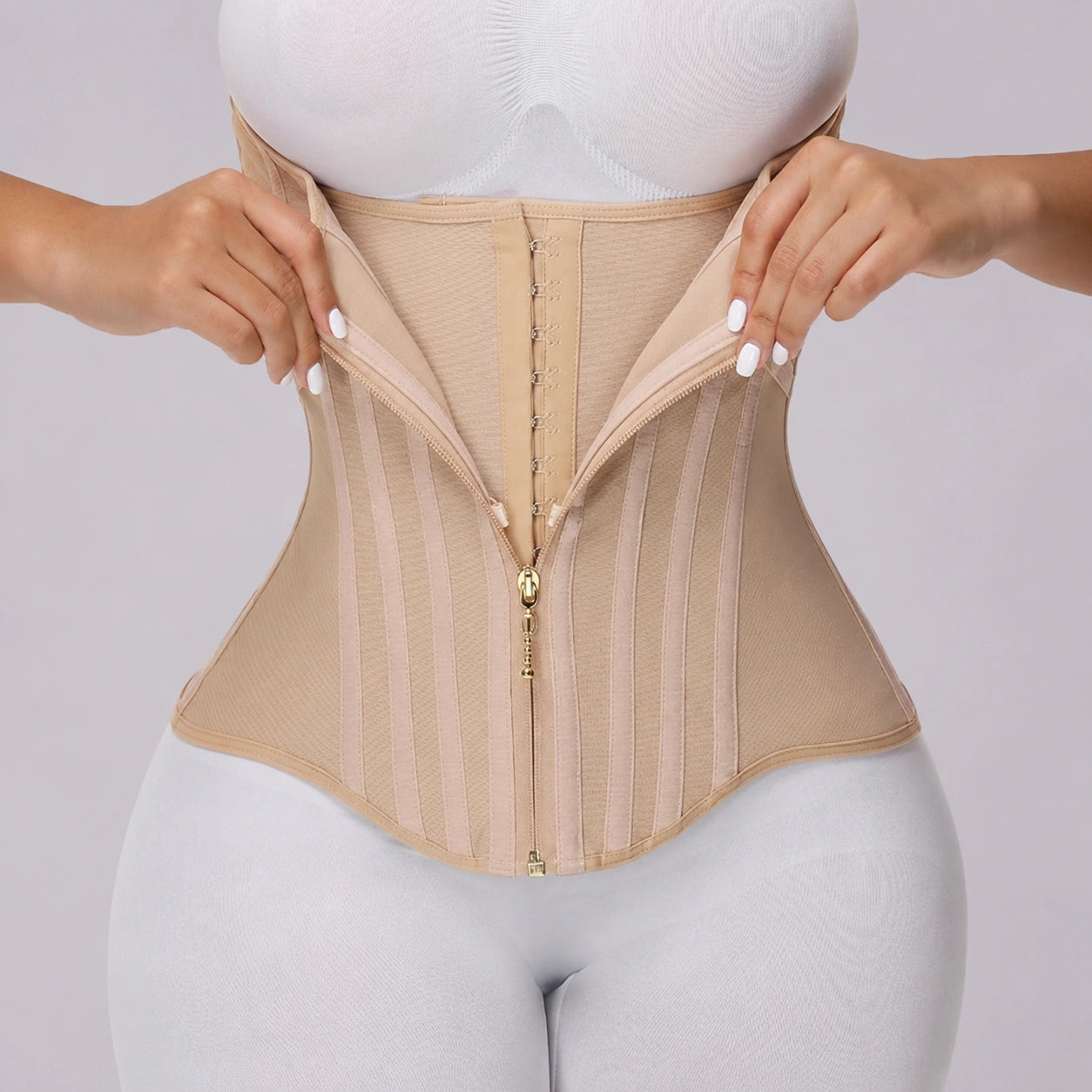 Close-up view of a beige waist training corset showing the adjustable front zipper, multiple hook fasteners, vertical shaping panels, and flexible side sections for a contoured fit.