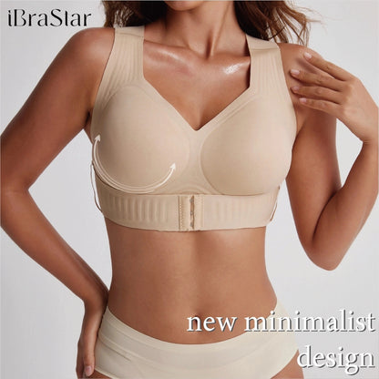 Close-up view of a model wearing a beige support bra with broad shoulder straps, a V-shaped neckline, molded cups, a wide adjustable underband, and a front hook closure, with arrows highlighting the lifting support design.