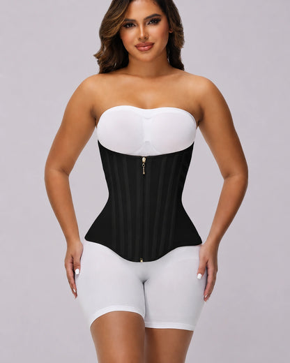 Full-body view of a model wearing a black waist cinching garment over white clothing, featuring a strapless style, front zipper closure, firm compression panels, and a defined hourglass shaping effect.